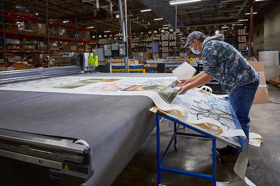 Person pulling artwork off assembly line